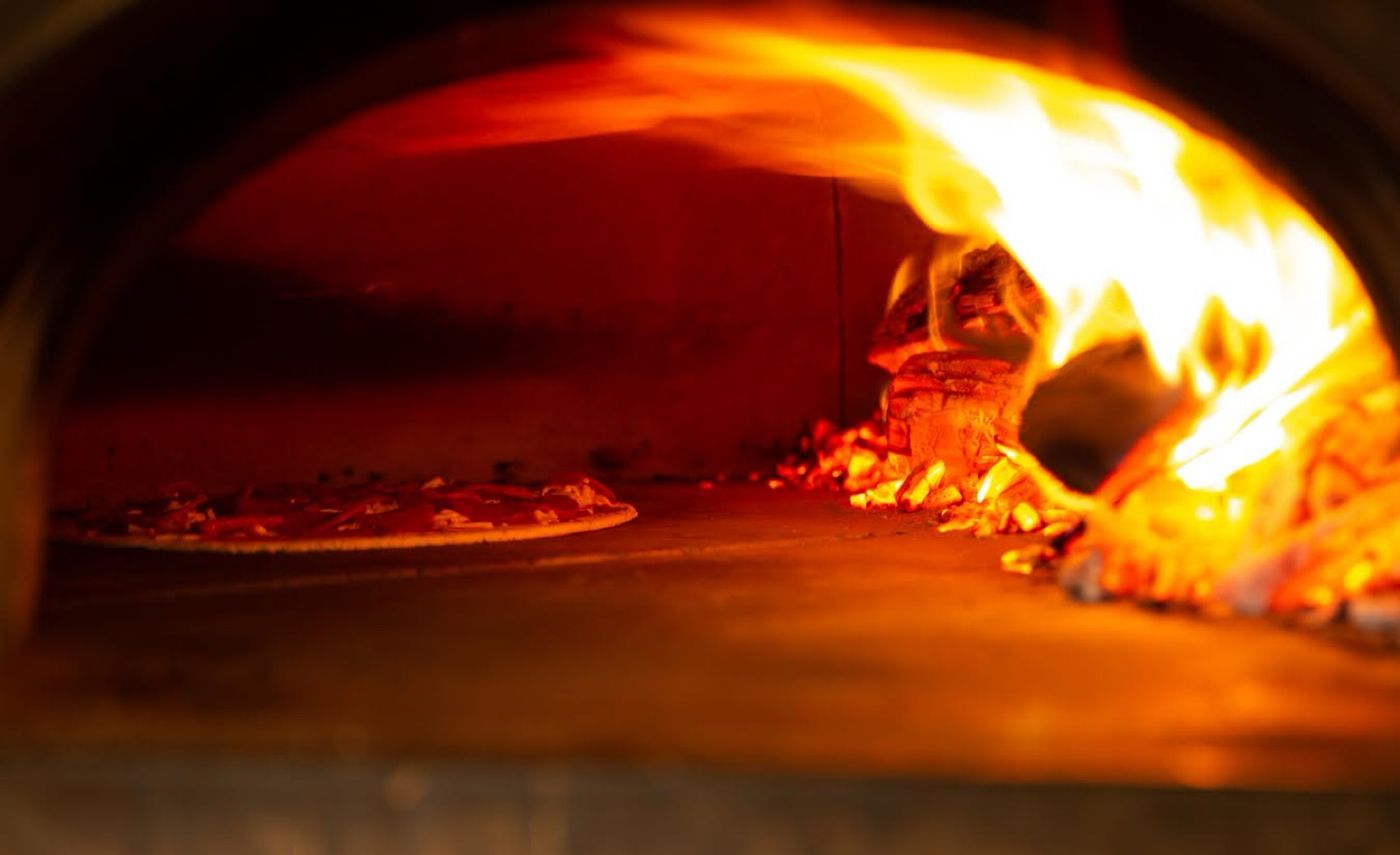 Flames curling across the floor of the wood-fired oven